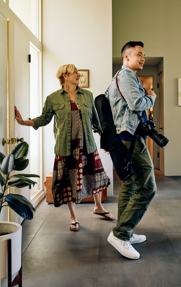 A Host shows a pro photographer the home. The photographer carries their gear in to photograph the home.