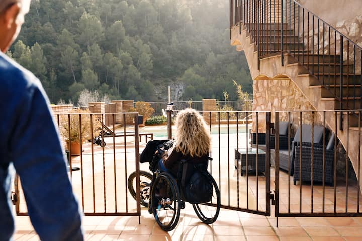 A wheelchair user with blonde hair enters a gated entrance.