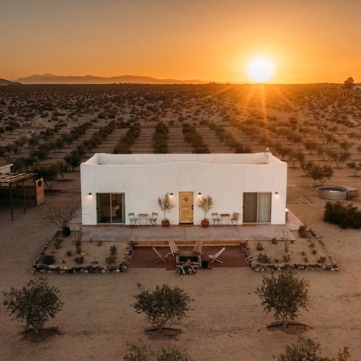 A modern desert farmhouse at sunset. 