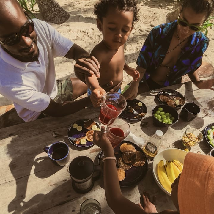 Top-down view of a young family enjoying a meal at a beachy picnic table. 