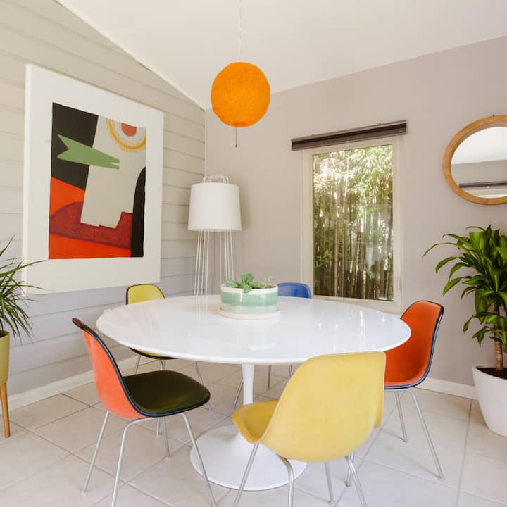 A white circular table sits in the middle of an colorful, artsy dining room.
