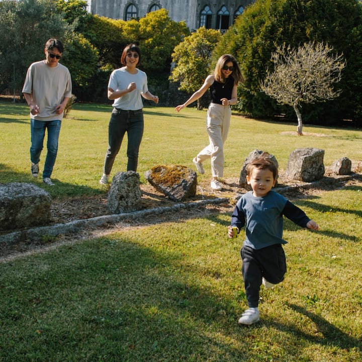 Two toddlers run around the grounds outside of a sunny castle.