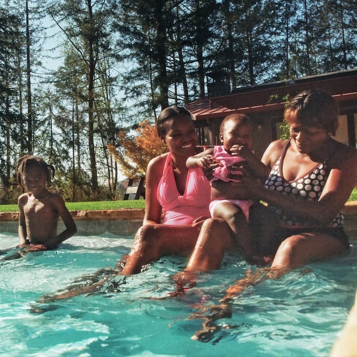 Three generations of a family happily splash around in an outdoor pool.