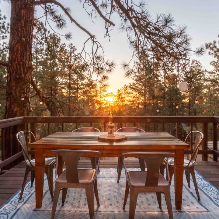 An outdoor dining table sits on a porch at sunset.