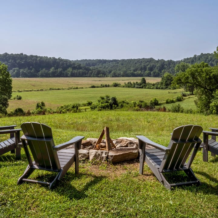 Four adirondack chairs surround a fire pit with an excellent view.  