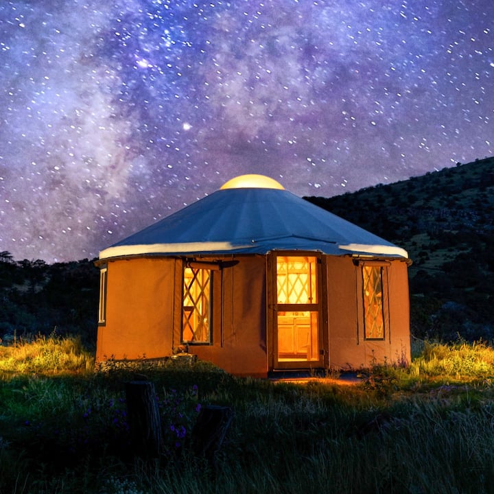 A cozy yurt sits under a sky brimming with stars.