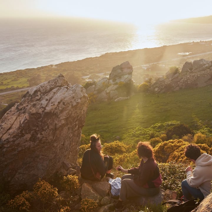 Three friends picnic on the hills near the California coast. 