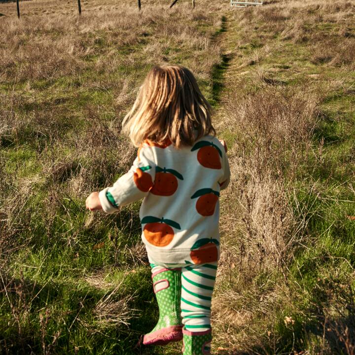 A toddler playfully runs up ahead on a hiking trail. 