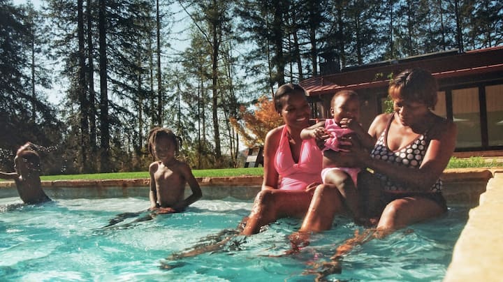 Three generations of a family happily splash around in an outdoor pool.