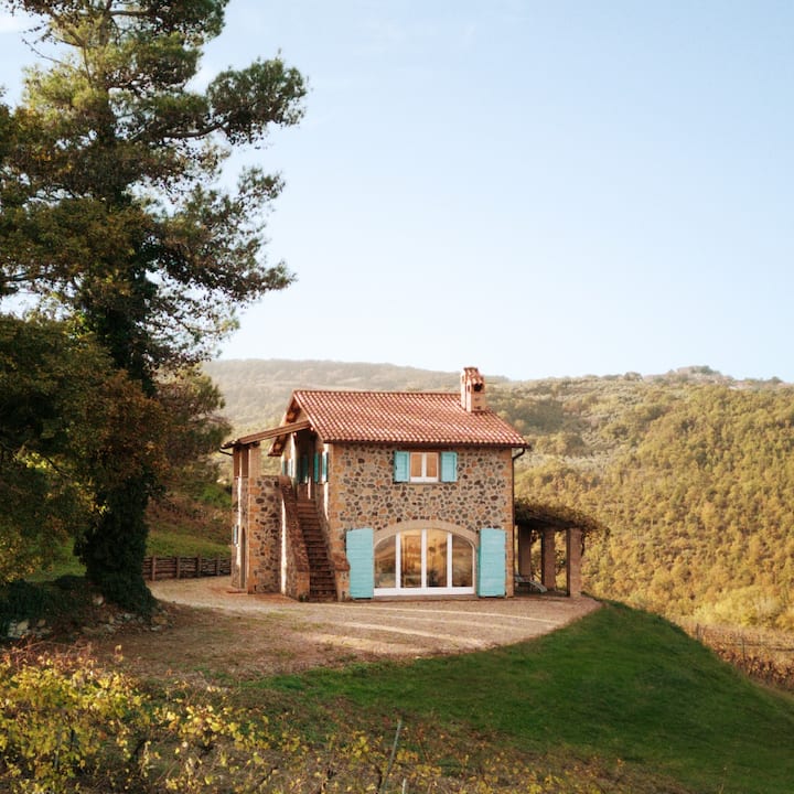 A picturesque stone house sits atop the Italian countryside. 