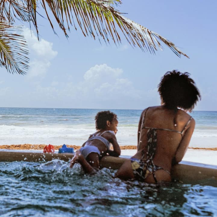A mother and baby enjoy a tropical ocean view from under the palm trees.