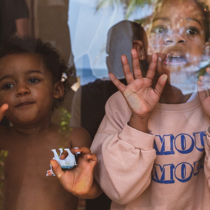 Two young kids press their faces against the glass to get their parents’ attention.