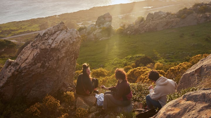 Three friends picnic on the hills near the California coast. 