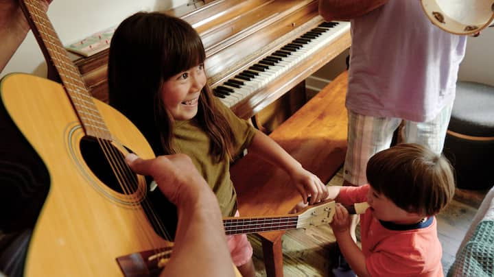 Two smiling kids dance and take part in a music class.