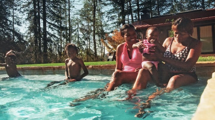 Three generations of a family happily splash around in an outdoor pool.