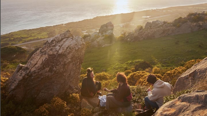 Three friends picnic on the hills near the California coast.