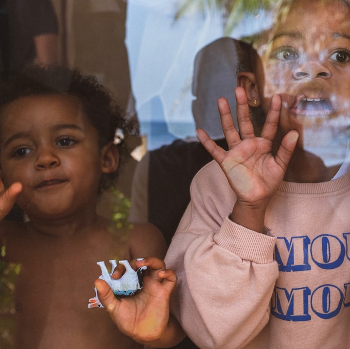 Two young kids press their faces against the glass to get their parents’ attention.