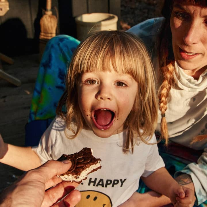 A toddler opens wide for an ice cream sandwich.