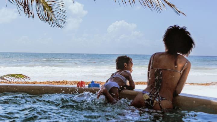 A mother and baby enjoy a tropical ocean view from under the palm trees.