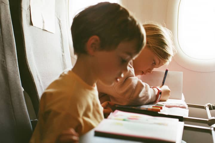 Two toddlers enjoy their coloring books while on a plane.