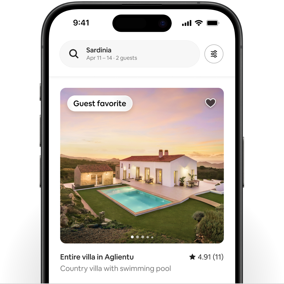 A phone shows an Airbnb listing of a white house in Sardinia. In the top-left corner of the listing is a Guest Favorite badge.