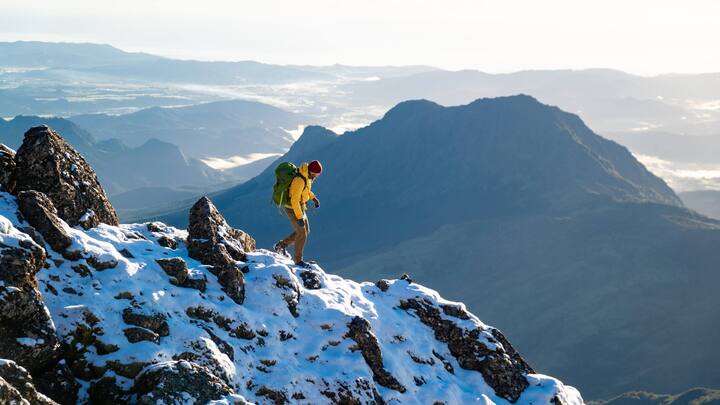 Man hikes over snow-capped mountain