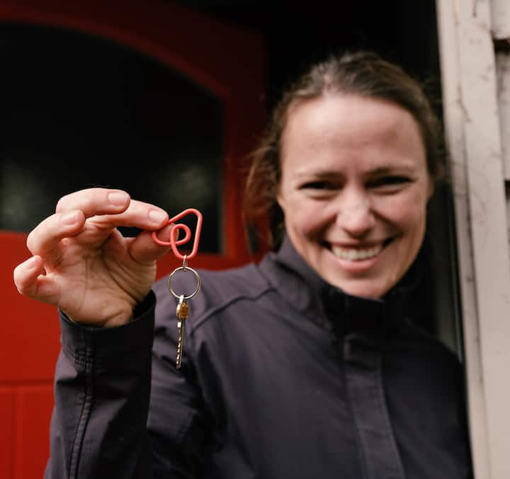 Airbnb host holds a key at their front door, smiling