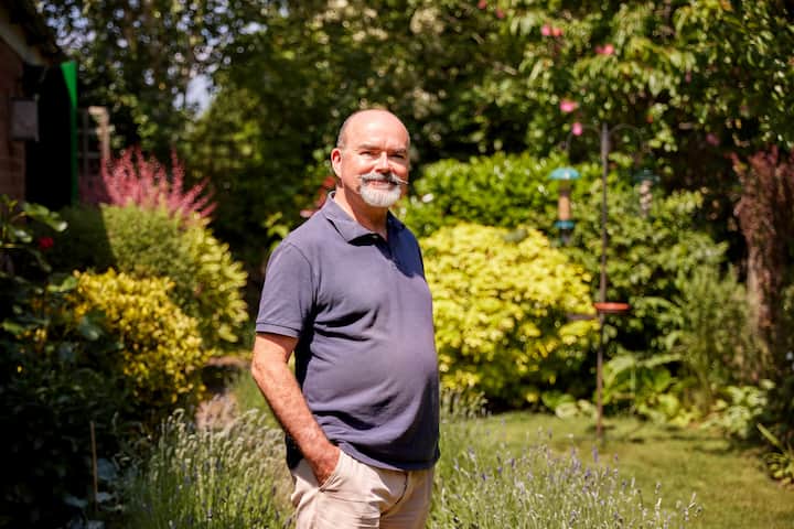 Image portrays superhost, Tim, smiling in his garden