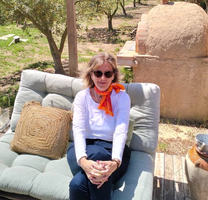 Pilar, a Spanish Host posing in her listing surrounded by Olive Groves