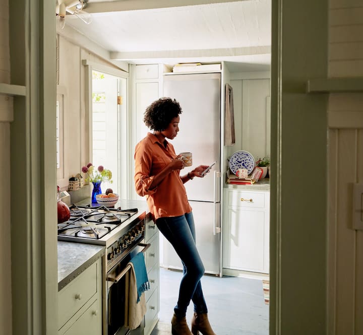 Woman reads something on her phone in a cosy looking kitchen