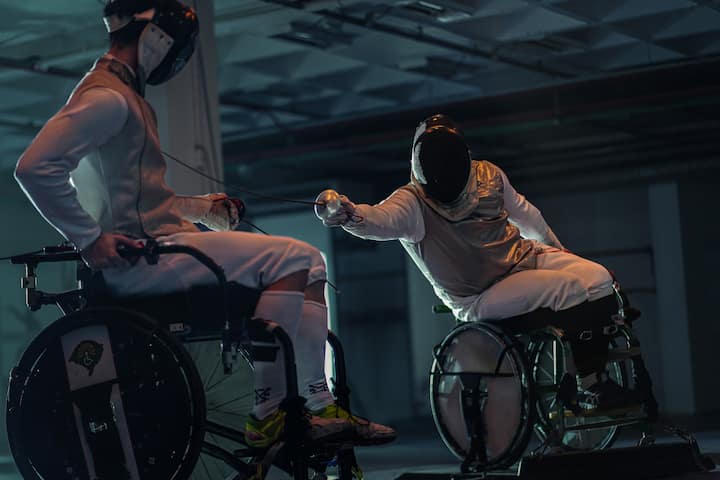 两名轮椅击剑手对练,其中一名击剑手的花剑击中了另一名击剑手的胸部。
