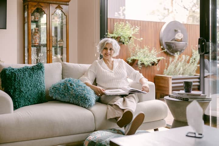 Best room host shiyanti sitting on a plush sofa with fluffy blue accent pillows
