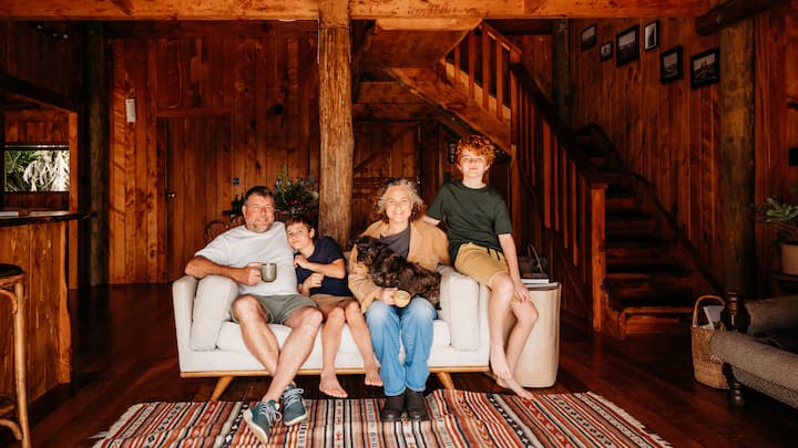 a family posed together on a couch in a handmade wooden cabin