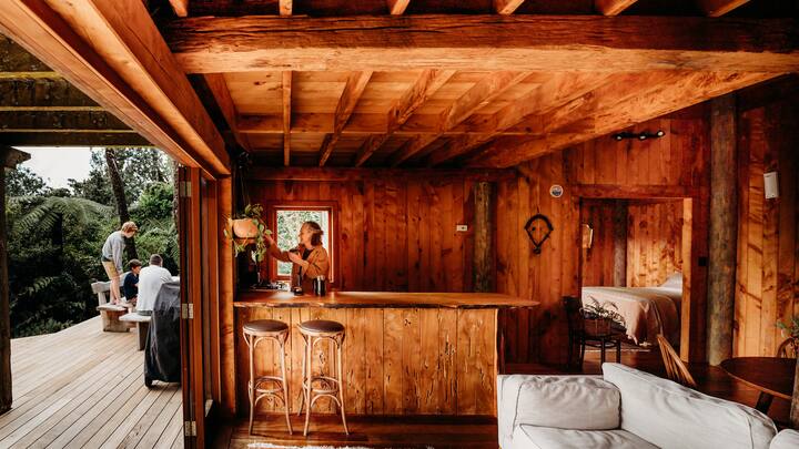 a handmade wooden property with a woman watering plants in the kitchen and a family on the deck