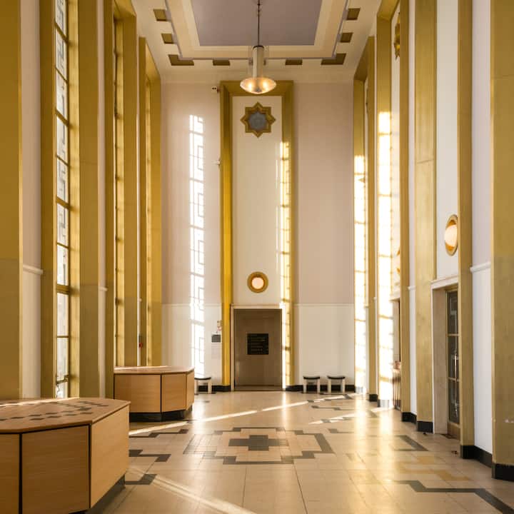 Interior of art deco building in Waltham Forest with tall windows and golden accents.