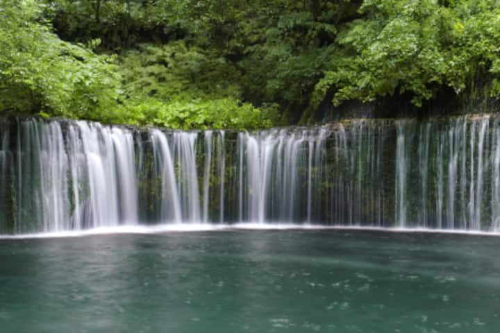 Image of a waterfall above a small, swimmable pond.