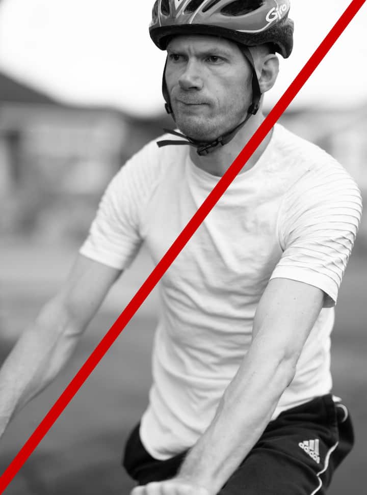 Close-up of a cyclist's torso and arms, with a blurred background. Image in black and white.
