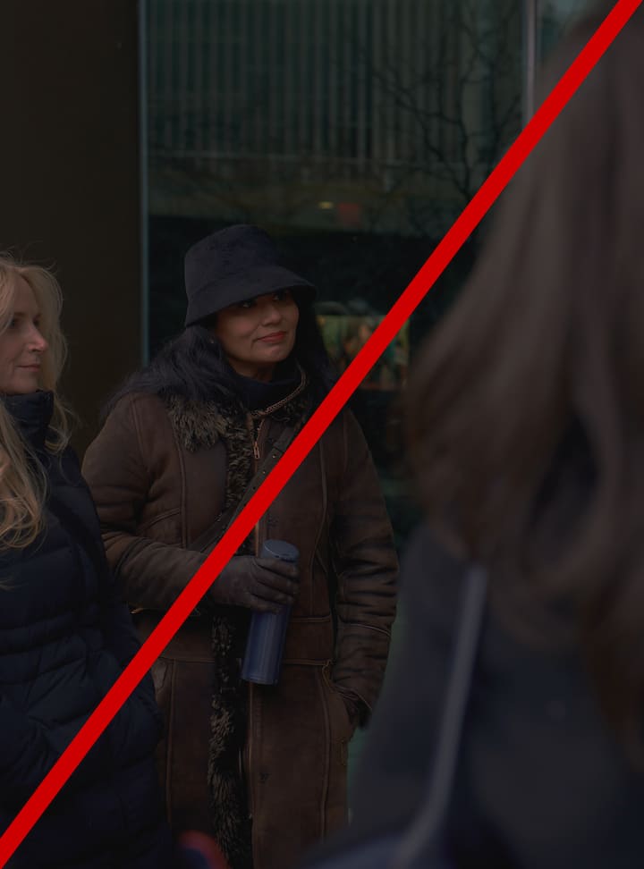 Three people wearing winter coats, one person holding a thermos, with a red diagonal line across the image indicating the image is too dark.