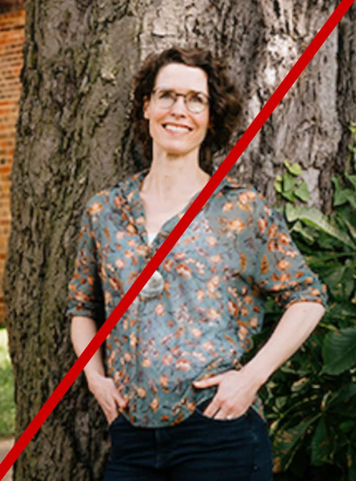 Person leaning against a tree trunk in nature, wearing a floral shirt and dark jeans. Image is blurry.