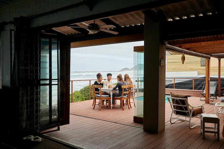 4 friends sitting at the table on a beachfront balcony