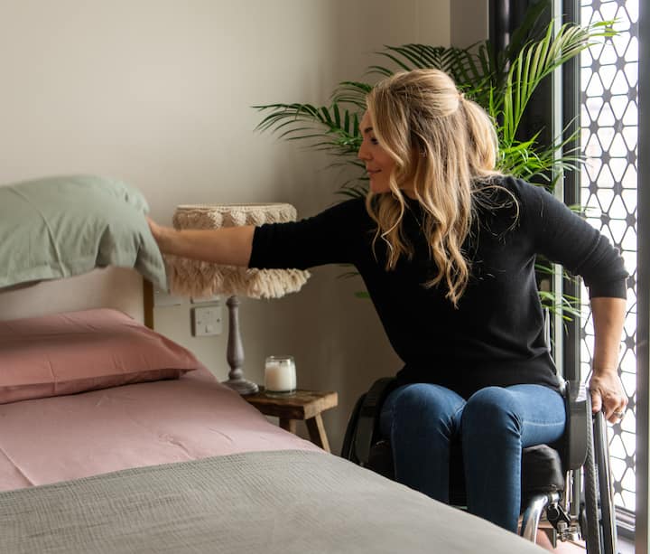 Woman wheelchair user makes bed