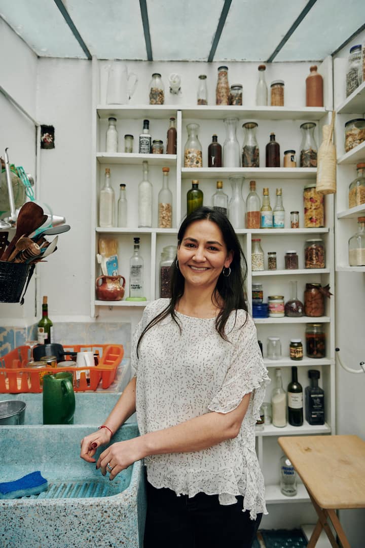 Woman smiles in a pantry full of sauces and bottles 