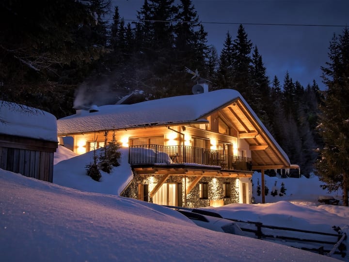 Gemütliches Holzchalet in Italien, umgeben von Schnee und hohen Bäumen