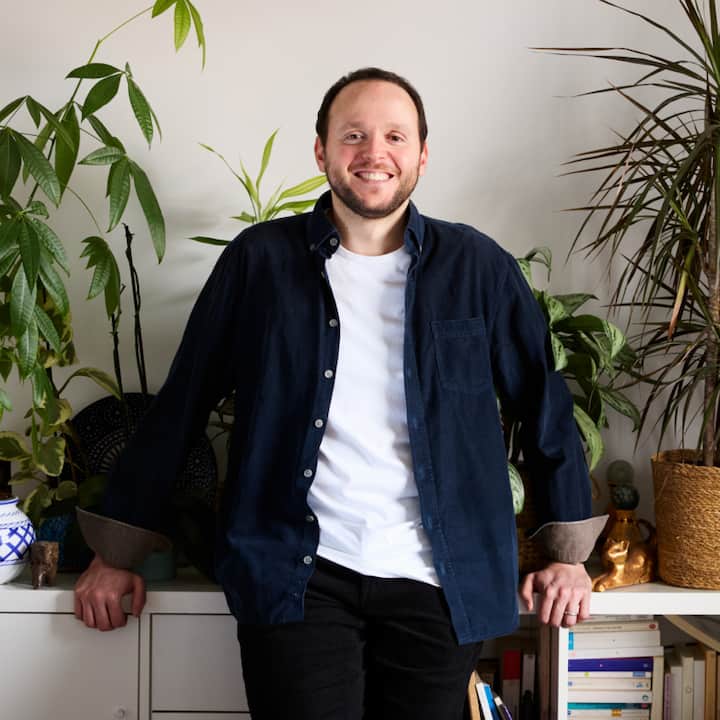  Lamine Madjoubi standing inside his listing leaning against a credenza with plants 