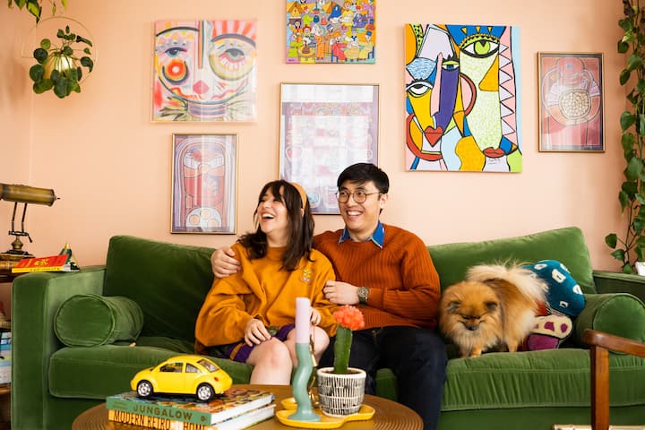 Hosts Simon and Hamas sit on green velvet couch surrounded by quirky modern details and custom art work