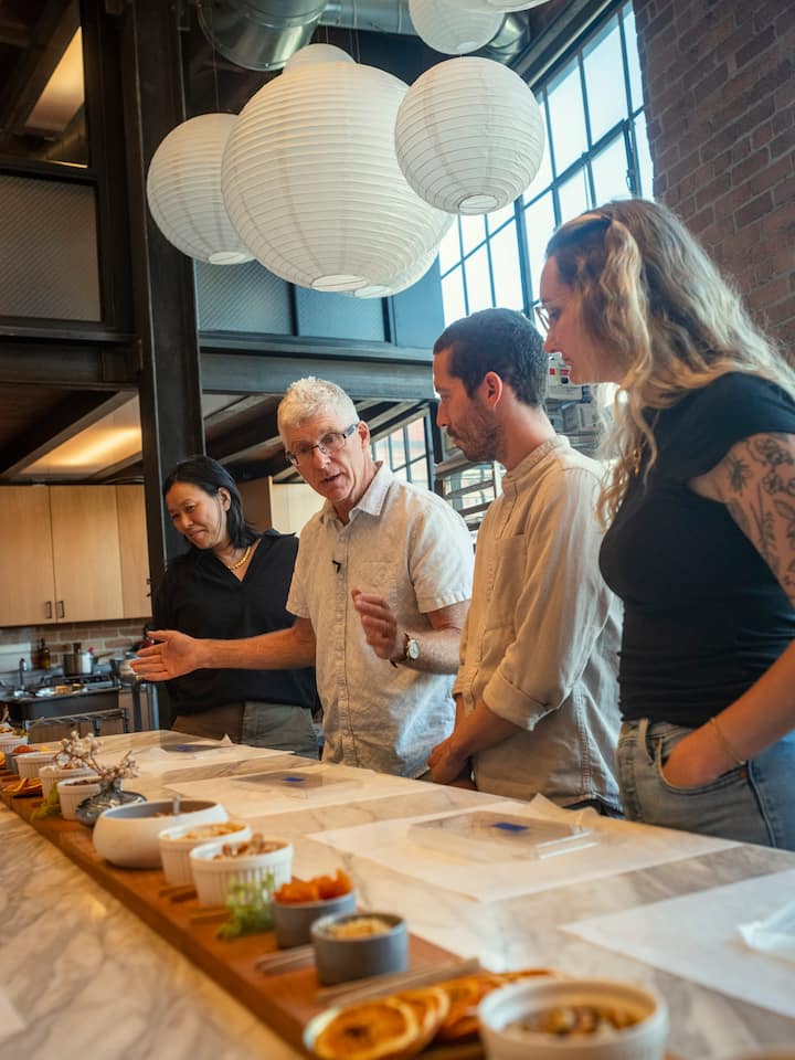 Group of people gathered around a kitchen counter, engaging in a chocolate-making class.