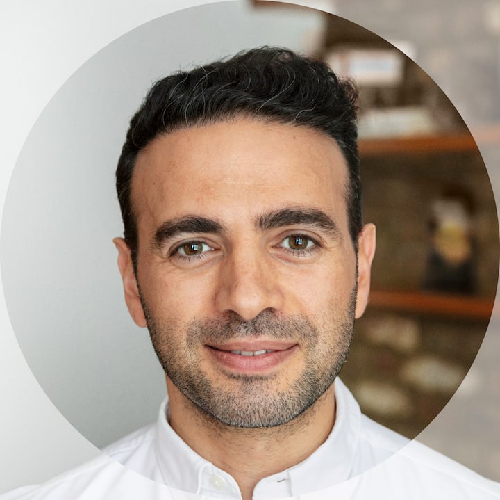 A person in a white shirt photographed indoors with a simple background.