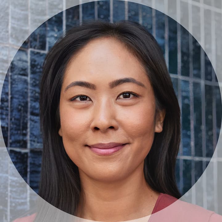 Close-up profile picture of a person with long dark hair, set against a blue tiled wall background.