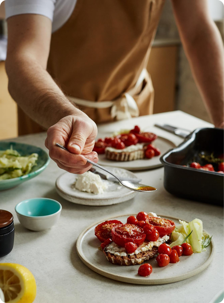 Close-up of chef's hand adding final touches to a plate, emphasizing attention to detail and professionalism in food presentation.