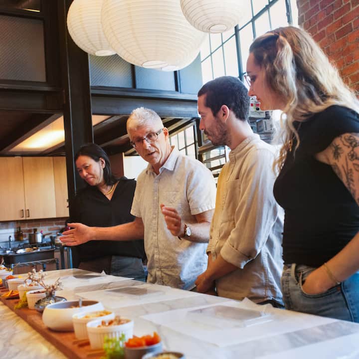 Les participants à un cours de cuisine discutent des différents ingrédients et plats disposés sur la table.